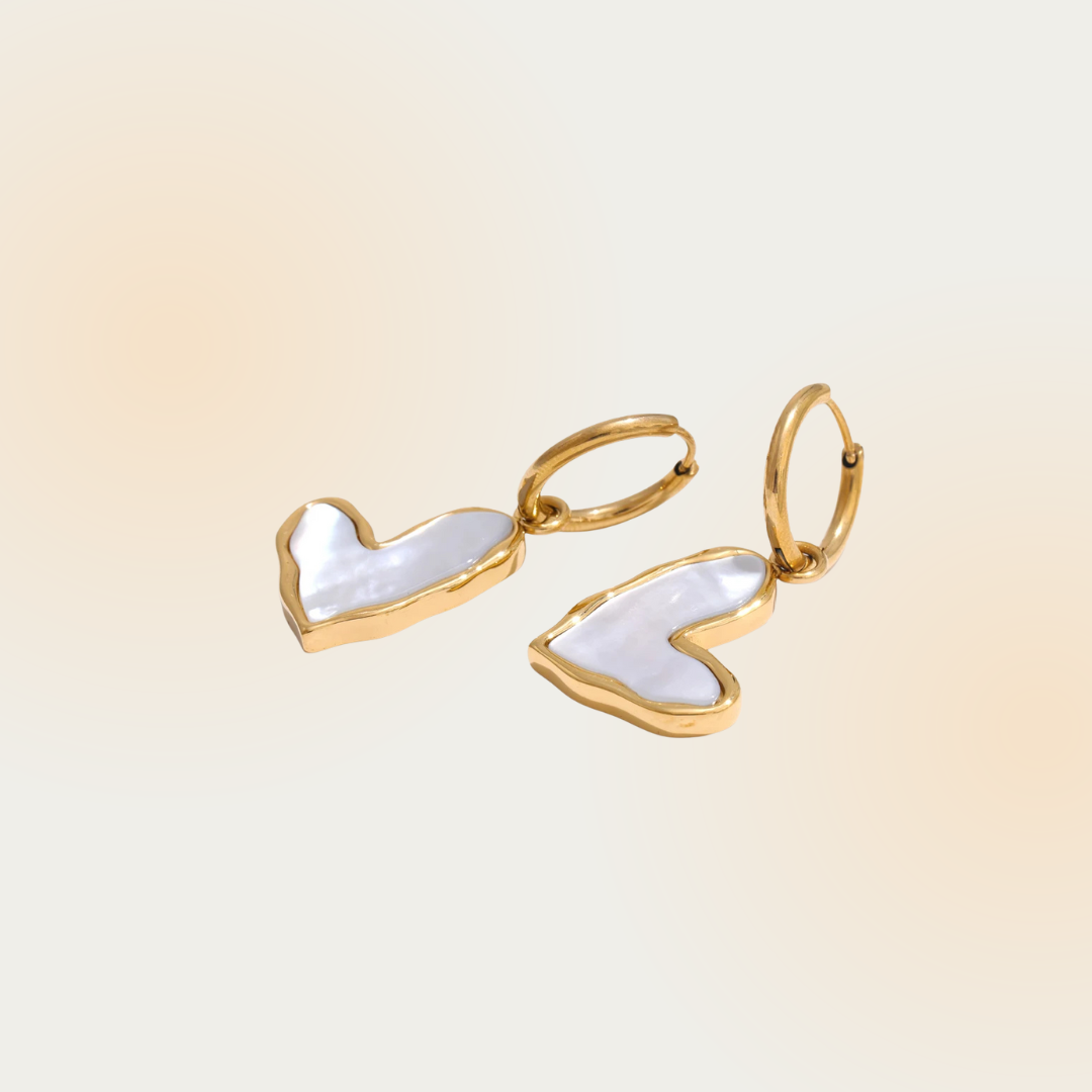 This image features a pair of gold hoop earrings with heart-shaped mother-of-pearl accents. The elegant design combines a glossy, iridescent finish with a luxurious gold frame, creating a chic and modern accessory.