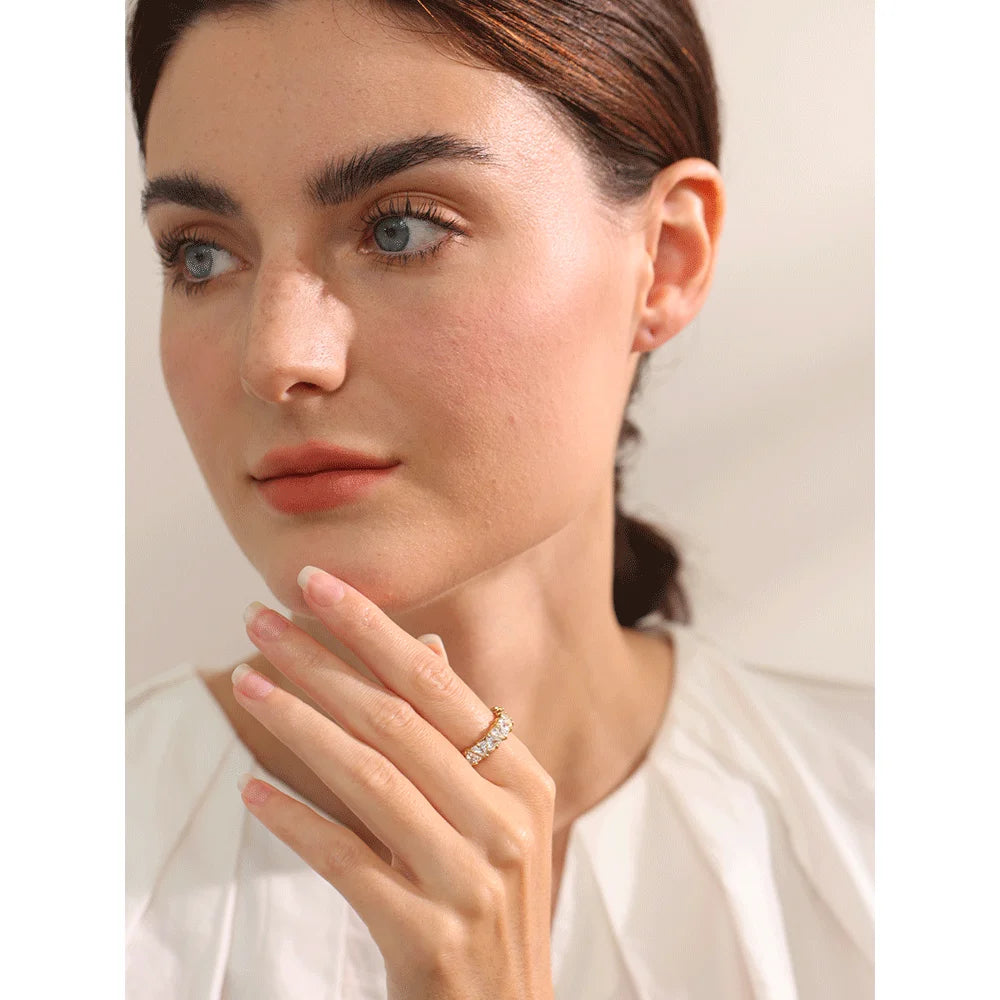 Close-up of a woman wearing a diamond ring on a neutral background