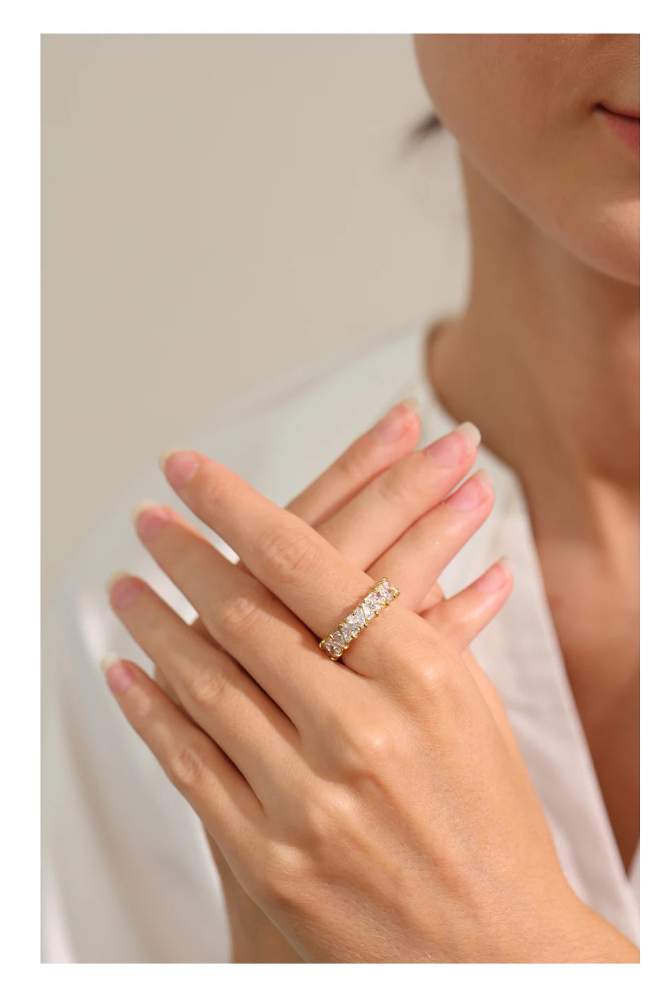 Close-up of a hand wearing a diamond ring with a neutral background