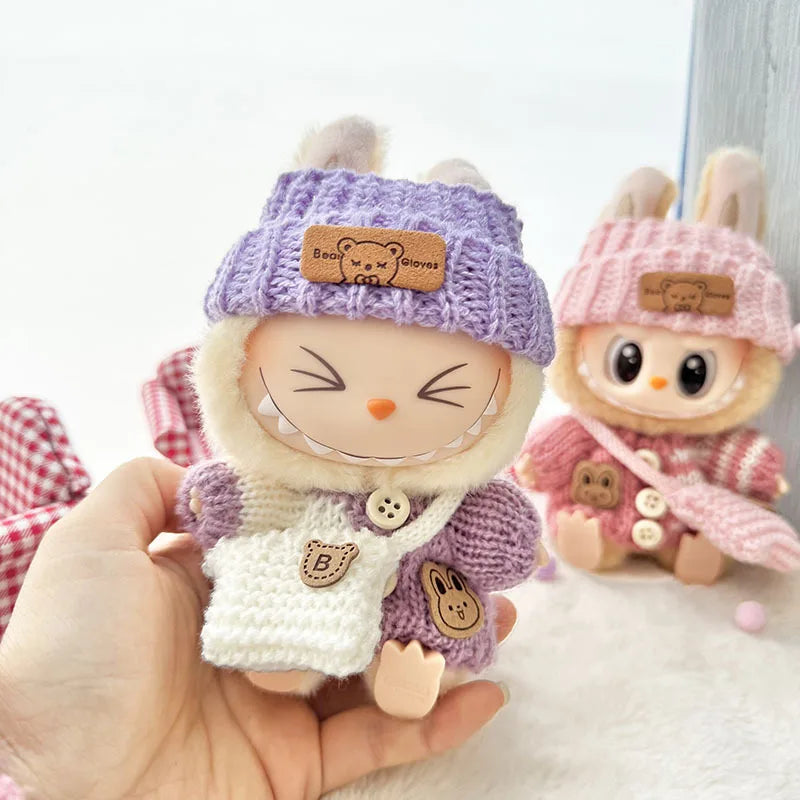 Two labubu cute plush toys with knitted hats and outfits on a white background