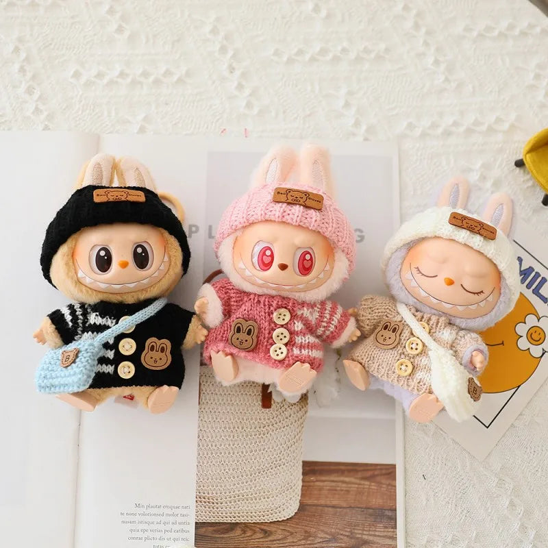 Three plush labubu toys with different outfits on a textured surface