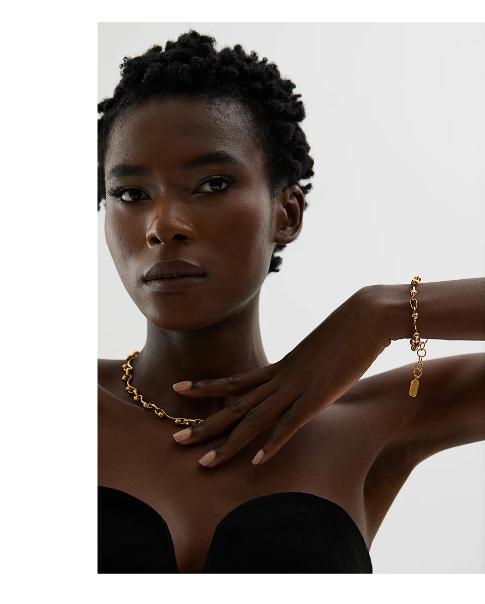 Woman wearing gold jewelry against a neutral background