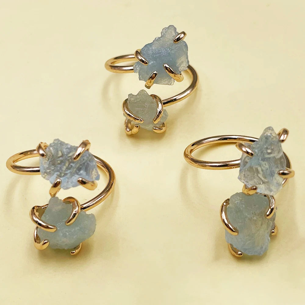 Gold rings with raw gemstones on a beige background