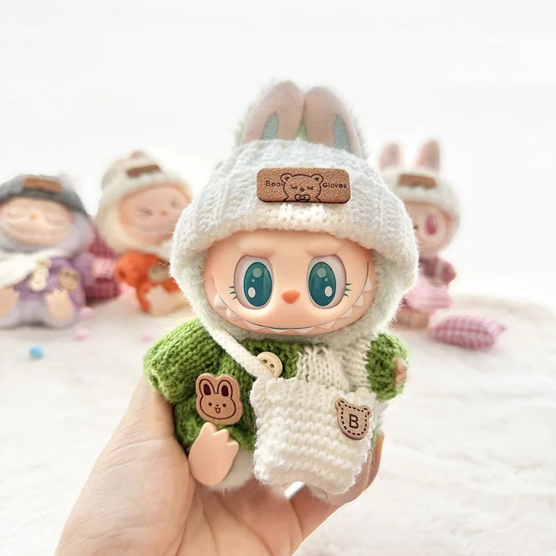 labubu toy figure with a white hat and green outfit held in a hand, with other similar toys in the background.