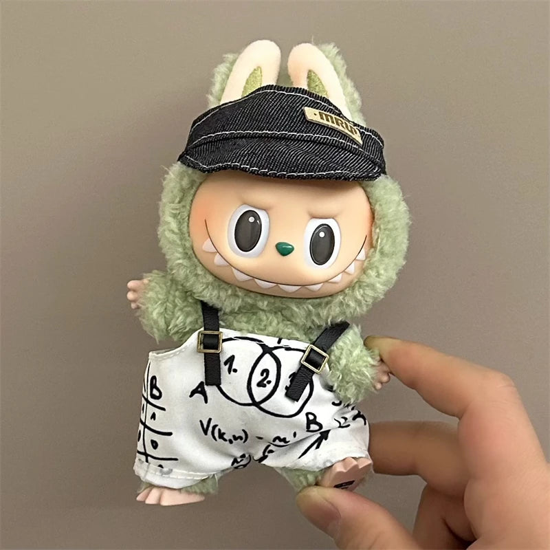 Small labubu plush toy with a black cap and white shirt with equations, held by a hand against a plain background.