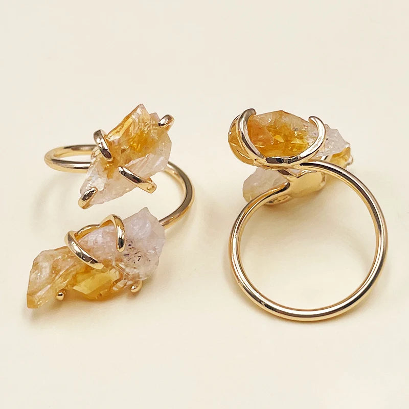 Gold rings with natural stone elements on a beige background