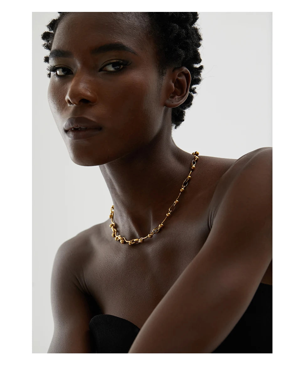 Woman wearing a gold necklace against a plain background