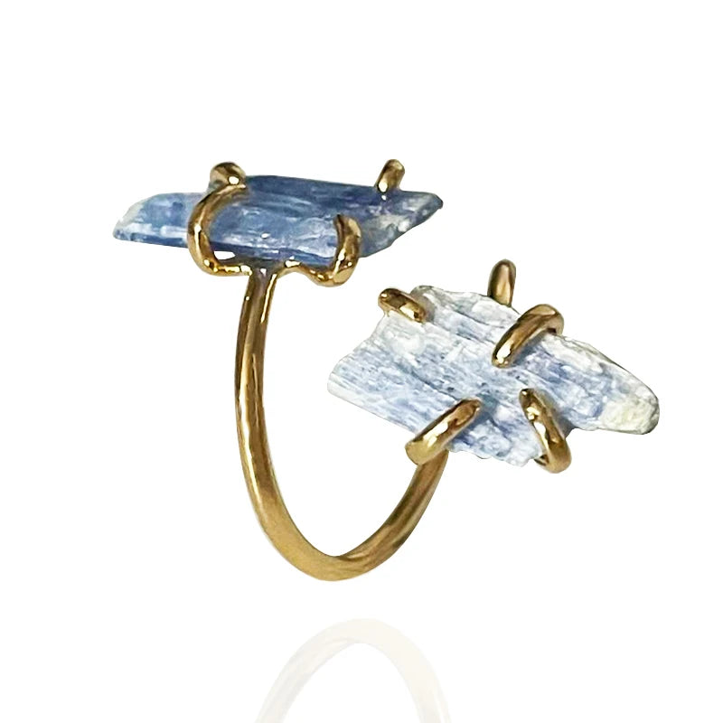 Gold-framed ring with blue and clear stone elements on a white background