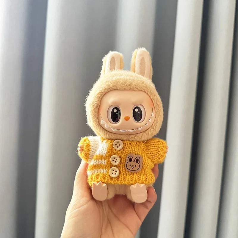 Labubu toy figure of a character wearing a yellow sweater with buttons, held against a neutral background.