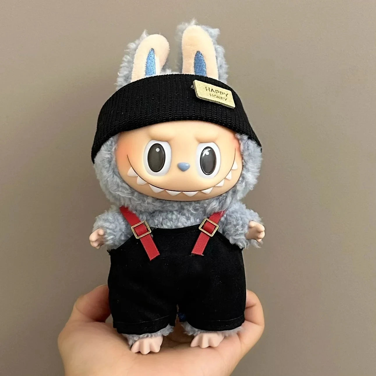 Toy figure with bunny ears, black shorts, and red suspenders held against a neutral background