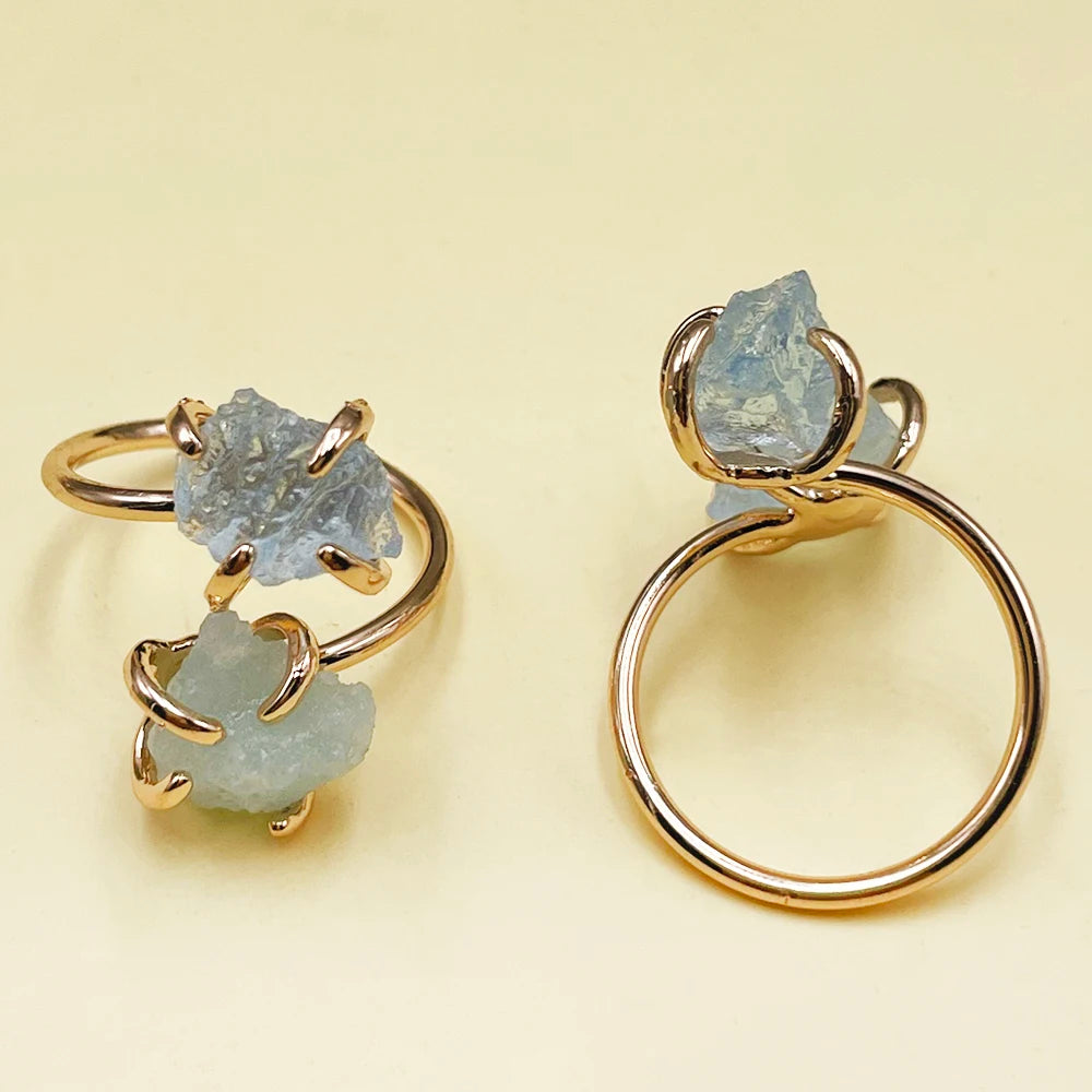 Gold rings with light blue gemstones on a beige background