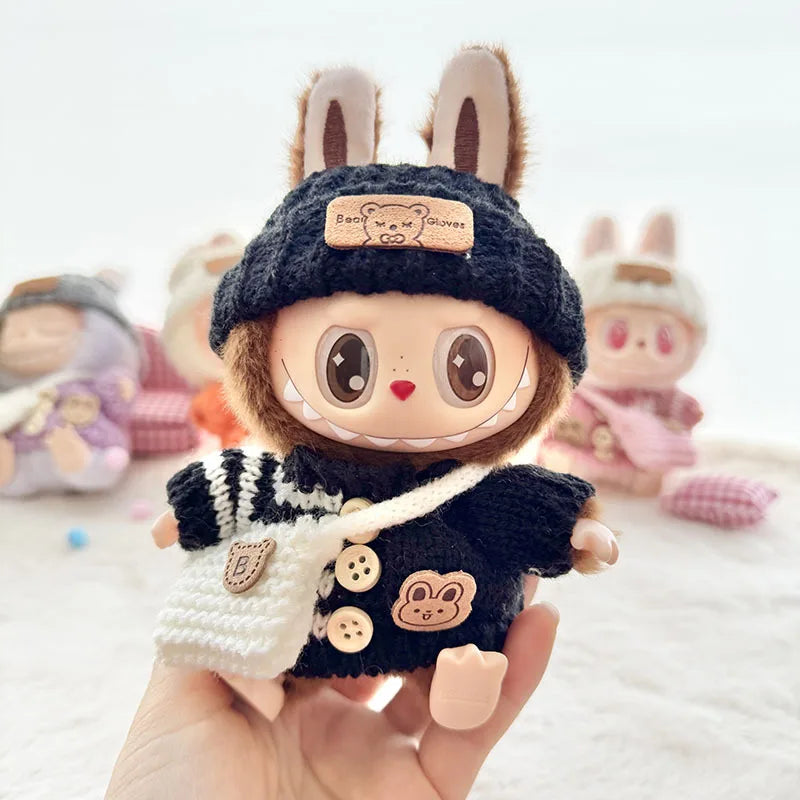 Labubu toy figure with bunny ears and a knitted outfit held in a hand against a soft focus background.