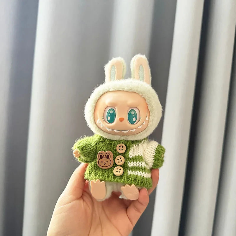 Labubu toy figure of a character wearing a green sweater with buttons, held against a neutral background.