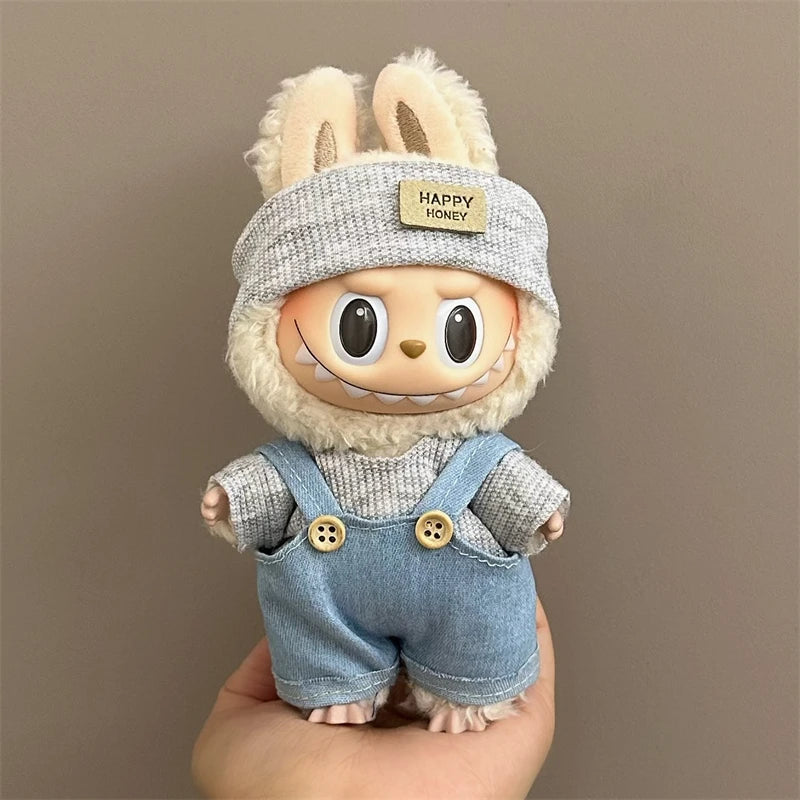 Labubu Toy figure with bunny ears and denim overalls held against a brown background