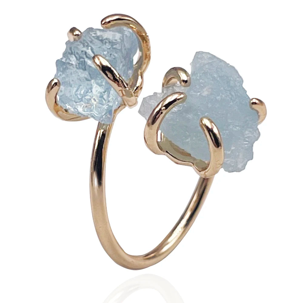 Gold ring with two large light blue stone elements on a white background