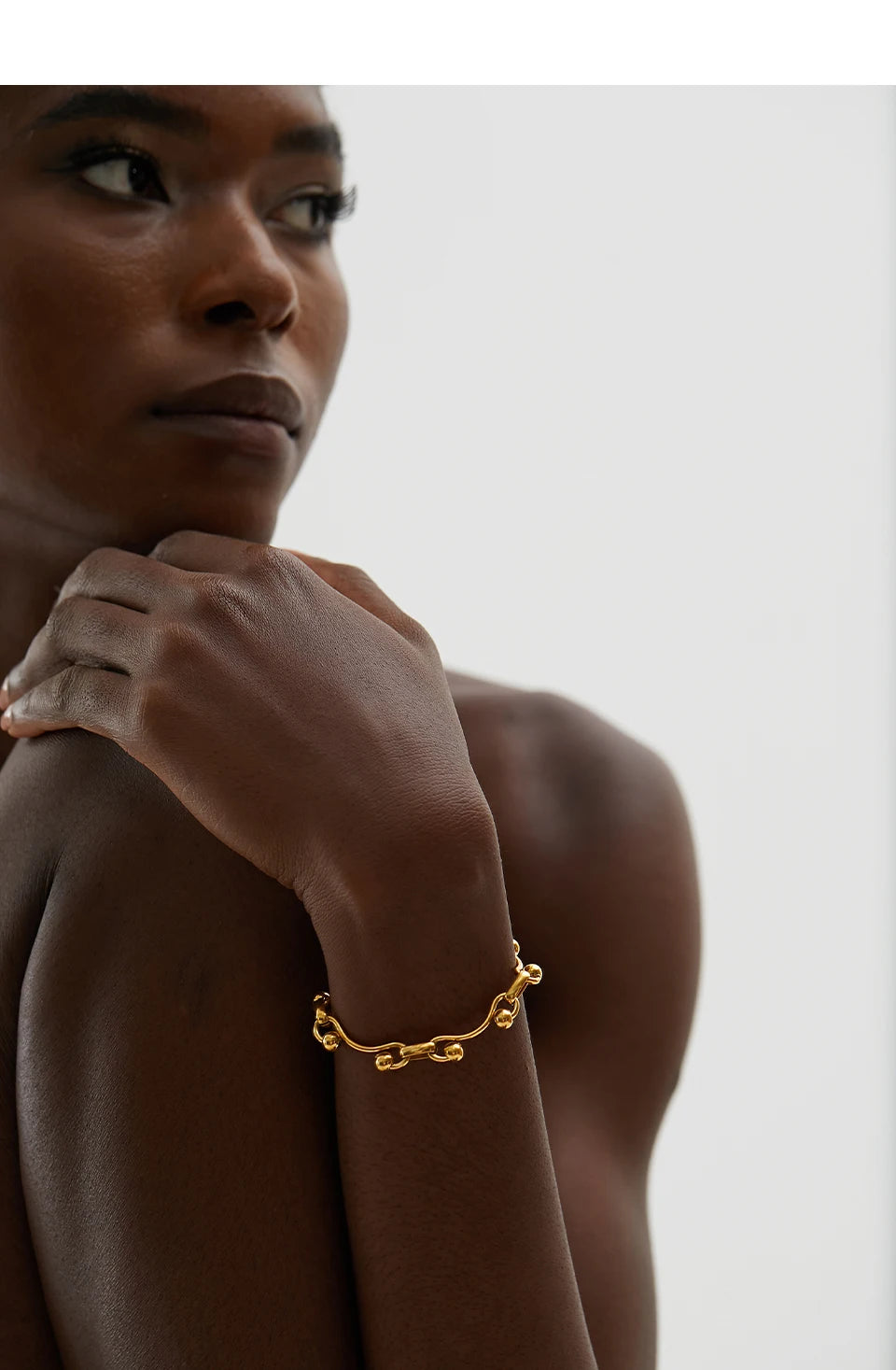 Woman wearing a gold bracelet on a plain background