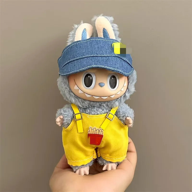Labubu Toy figure with a denim cap and yellow overalls held against a plain background
