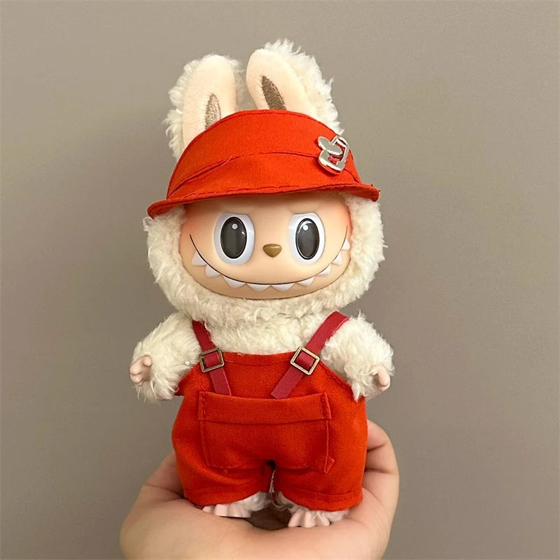 Plush Labubu toy with a red hat and overalls held in a hand against a plain background