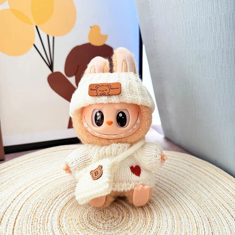 Plush labubu toy with a white hat and scarf on a textured surface