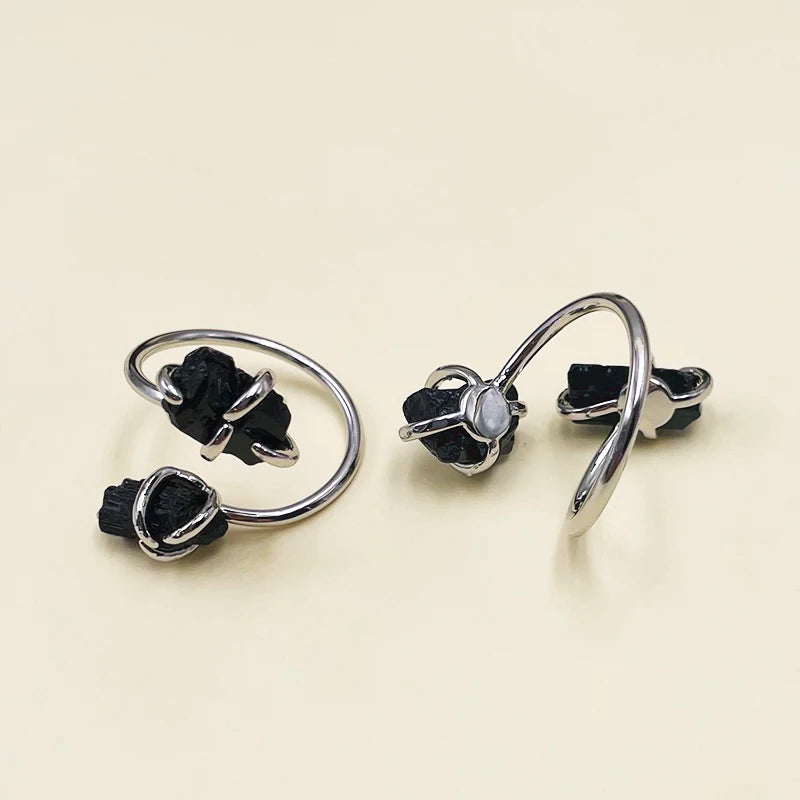 Pair of silver rings with black gemstones on a beige background