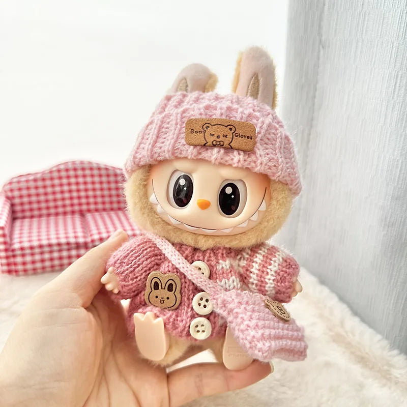 Cute labubu plush toy with a pink hat and coat held by a hand against a light background
