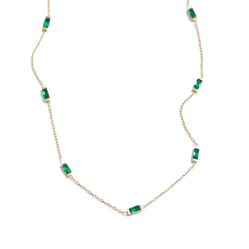 Gold necklace with green gemstones on a white background