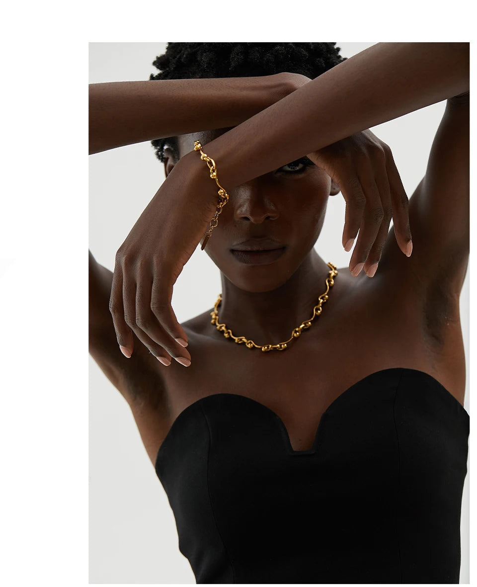 Woman wearing a gold chain necklace with a plain background