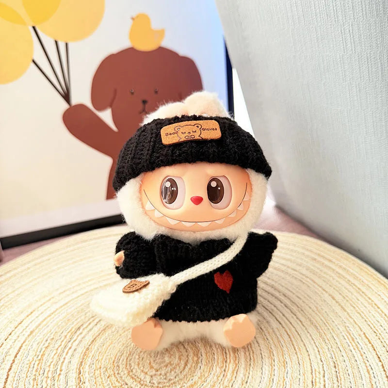 Cute labubu plush toy with a black hat and scarf on a textured surface